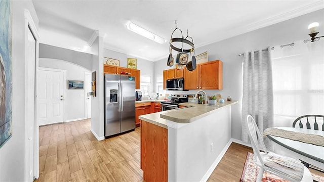 kitchen with stainless steel appliances, light wood-type flooring, a peninsula, and light countertops