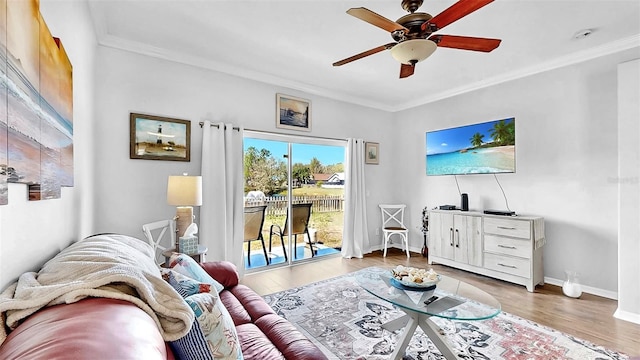 living area with a ceiling fan, crown molding, baseboards, and wood finished floors