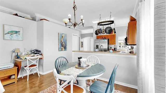 dining space with ornamental molding, an inviting chandelier, and light wood-style floors