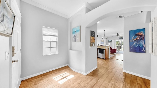 interior space featuring visible vents, arched walkways, baseboards, ornamental molding, and light wood-type flooring