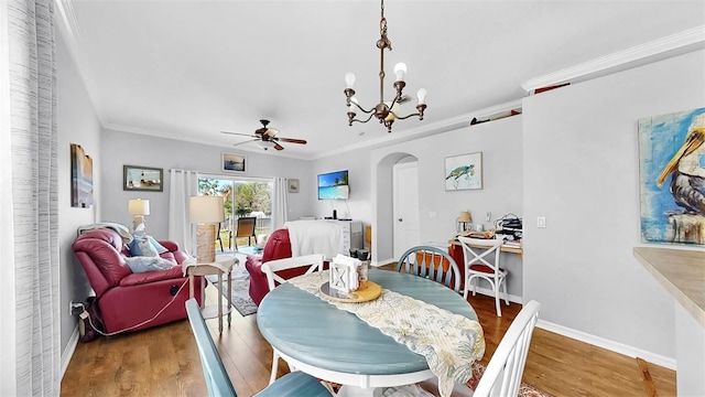 dining room with arched walkways, crown molding, baseboards, and wood finished floors