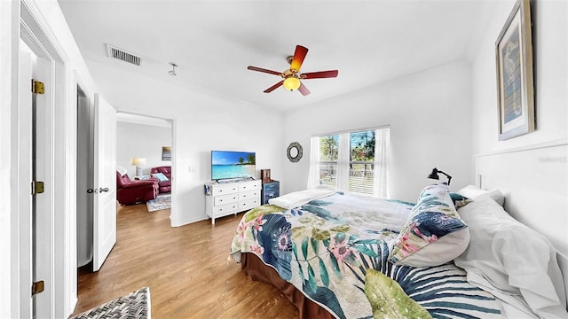 bedroom featuring wood finished floors, visible vents, and a ceiling fan