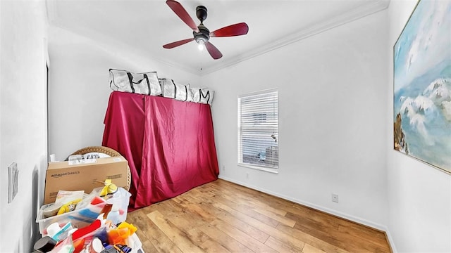 bedroom with ornamental molding, a ceiling fan, baseboards, and hardwood / wood-style flooring