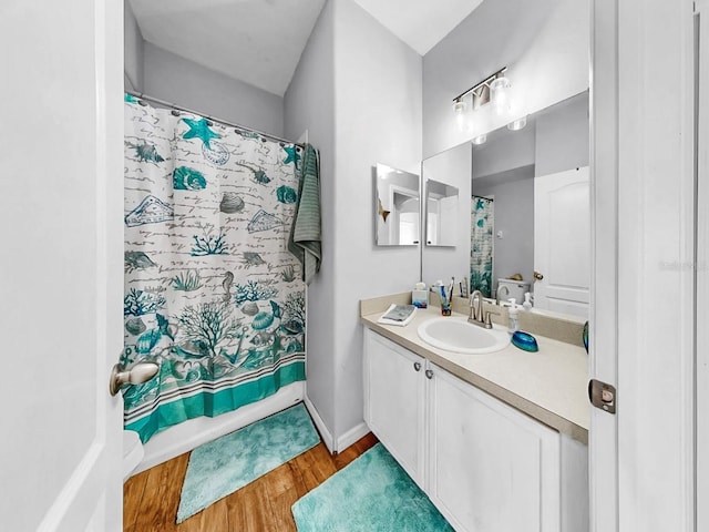 full bathroom featuring wood finished floors, vanity, and baseboards