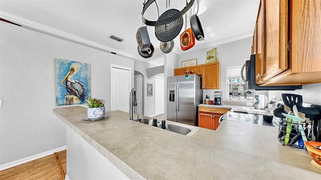 kitchen featuring crown molding, visible vents, appliances with stainless steel finishes, brown cabinetry, and a sink