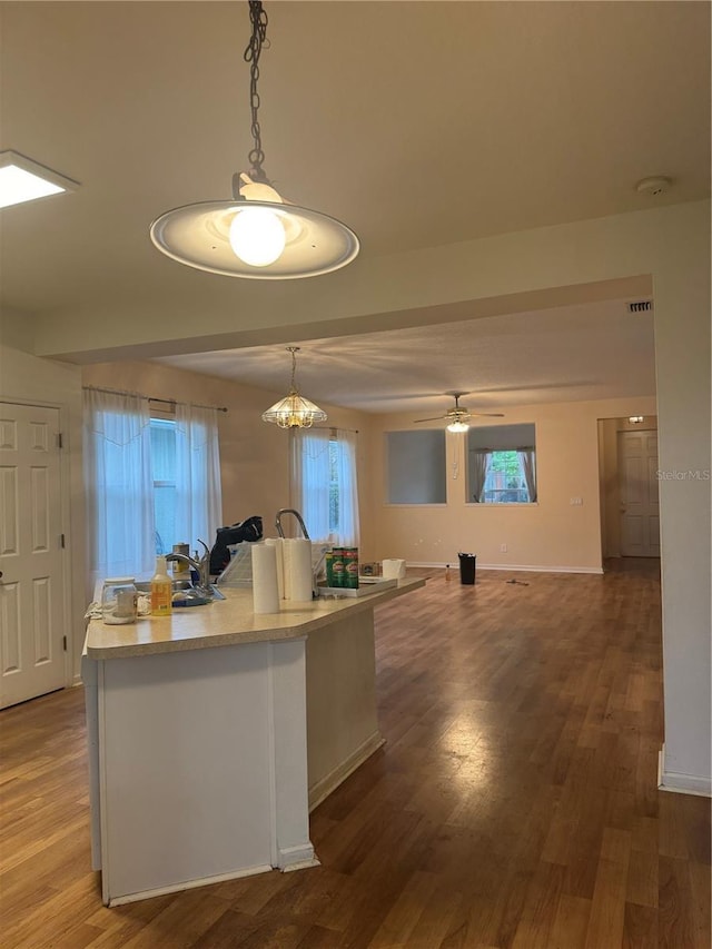 kitchen with light countertops, decorative light fixtures, baseboards, and wood finished floors