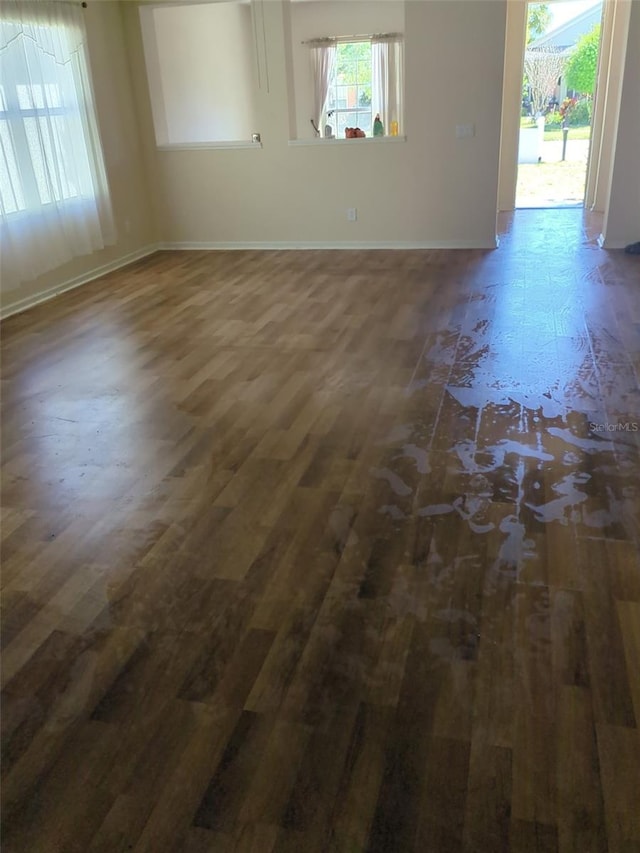 spare room featuring plenty of natural light, wood finished floors, and baseboards
