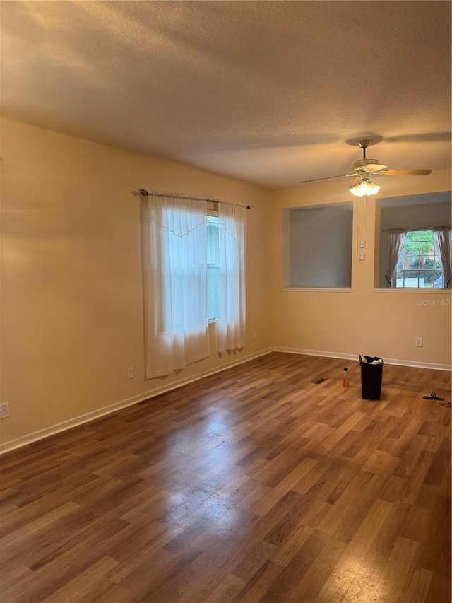 empty room featuring a ceiling fan, a textured ceiling, baseboards, and wood finished floors