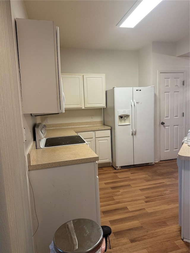 kitchen with electric range oven, light countertops, light wood-type flooring, white fridge with ice dispenser, and white cabinetry