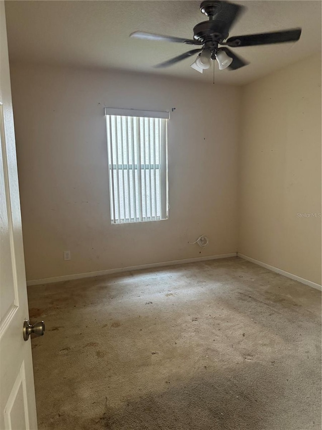 carpeted empty room with baseboards and a ceiling fan