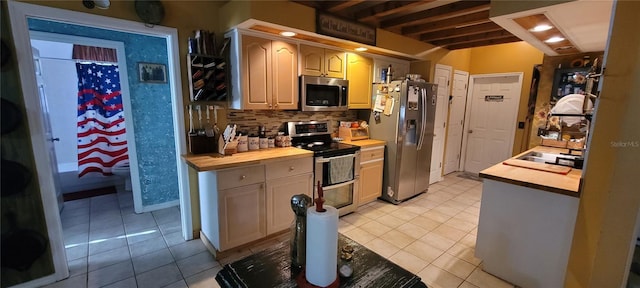 kitchen featuring a sink, wood counters, tasteful backsplash, appliances with stainless steel finishes, and light tile patterned flooring