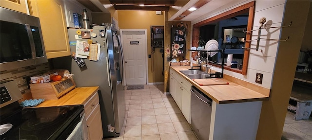 kitchen featuring a sink, butcher block countertops, tasteful backsplash, and stainless steel appliances