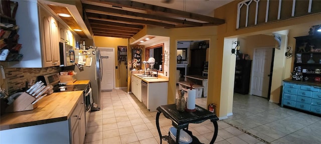 kitchen with light tile patterned floors, wooden counters, stainless steel appliances, and a sink