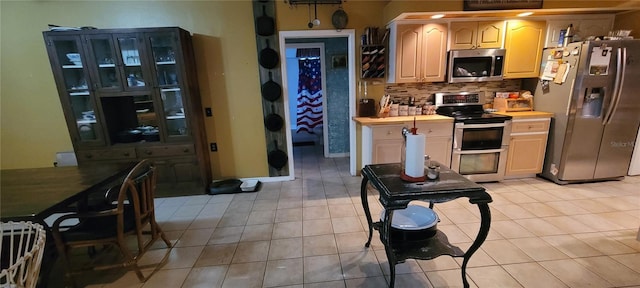 kitchen featuring decorative backsplash, appliances with stainless steel finishes, and light tile patterned flooring