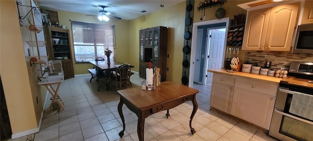 kitchen featuring light tile patterned flooring, ceiling fan, butcher block countertops, stainless steel appliances, and tasteful backsplash