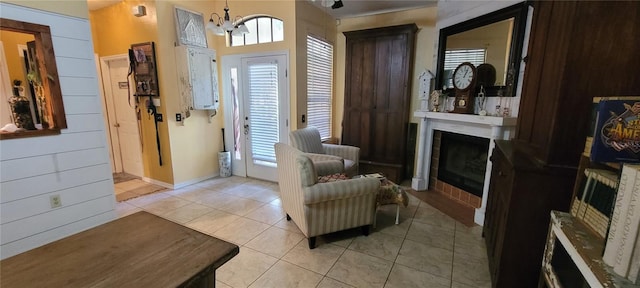 foyer entrance with light tile patterned flooring, a chandelier, and a fireplace