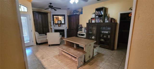 dining area featuring light tile patterned flooring, a fireplace, and ceiling fan