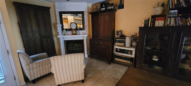 living area with light tile patterned floors, a fireplace, and ceiling fan