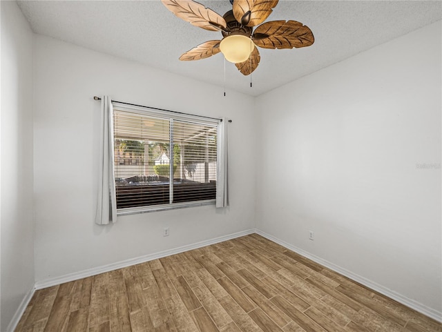 spare room featuring ceiling fan, a textured ceiling, baseboards, and wood finished floors