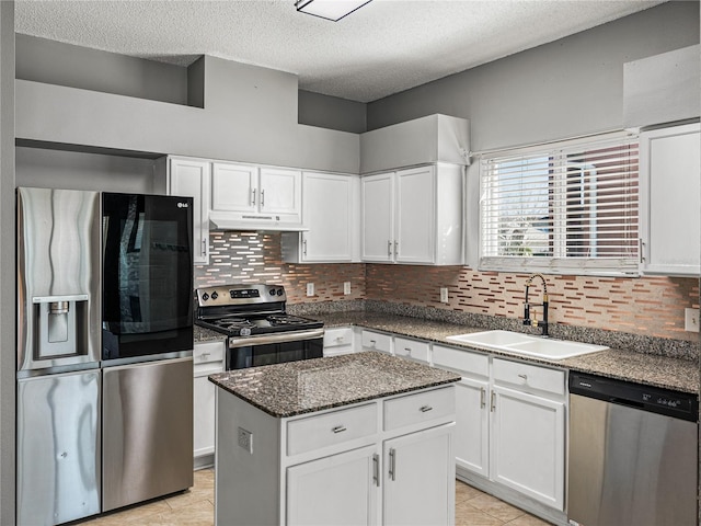 kitchen with a center island, backsplash, appliances with stainless steel finishes, white cabinets, and a sink