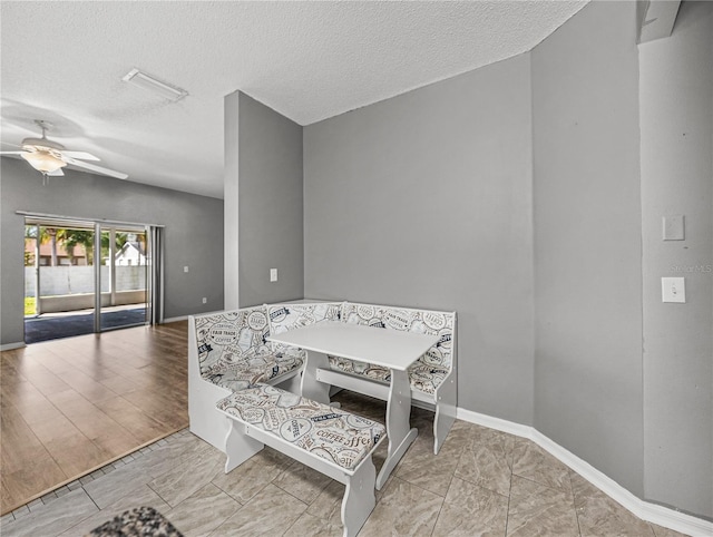 dining area featuring ceiling fan, baseboards, and a textured ceiling