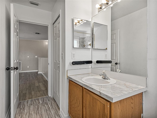 bathroom featuring baseboards, visible vents, wood finished floors, and vanity