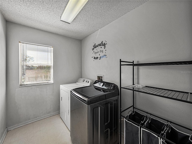 laundry area featuring light floors, a textured ceiling, washer and dryer, laundry area, and baseboards