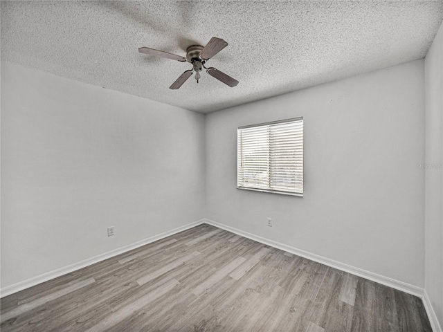 empty room featuring ceiling fan, a textured ceiling, baseboards, and wood finished floors