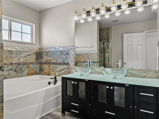 full bath featuring a bath, double vanity, visible vents, and a sink