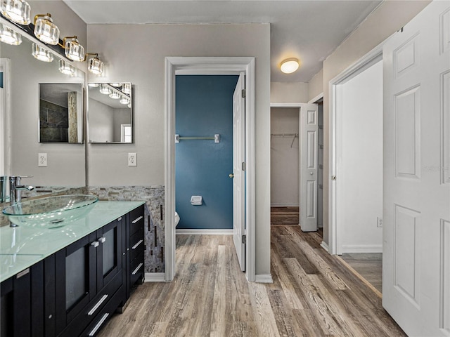 full bathroom featuring toilet, a spacious closet, wood finished floors, and vanity