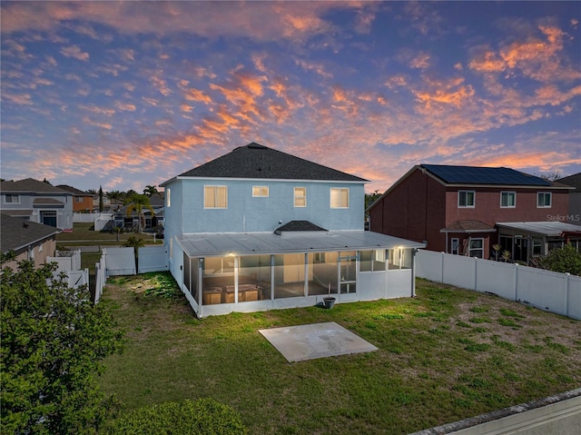 back of house featuring a yard, a patio area, a fenced backyard, and a sunroom