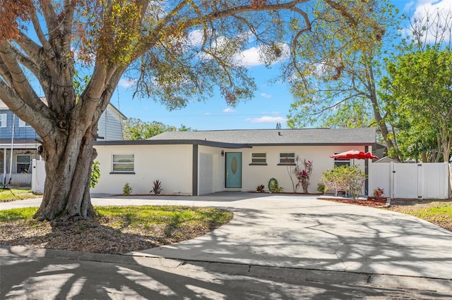 ranch-style house with driveway, fence, a gate, and stucco siding