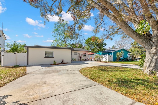 single story home with driveway, fence, a front lawn, and stucco siding