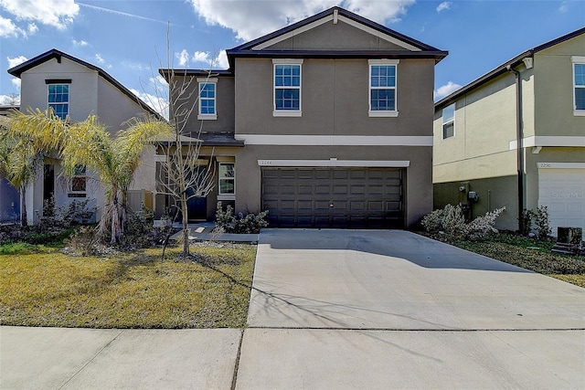 traditional-style home with driveway, an attached garage, and stucco siding