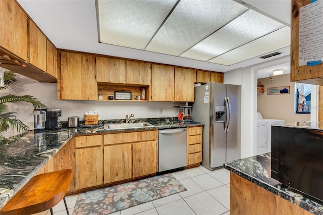 kitchen featuring light tile patterned floors, visible vents, dark stone counters, appliances with stainless steel finishes, and a sink