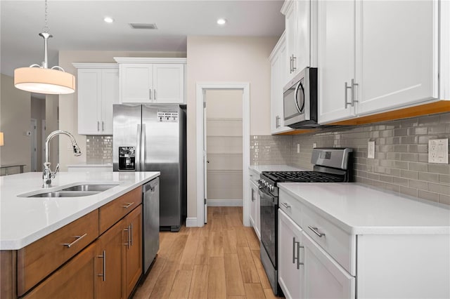 kitchen featuring appliances with stainless steel finishes, light countertops, white cabinetry, and a sink