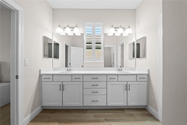 full bath featuring double vanity, wood tiled floor, baseboards, and a sink