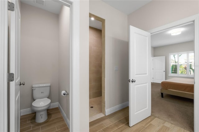 ensuite bathroom featuring visible vents, baseboards, toilet, wood tiled floor, and walk in shower