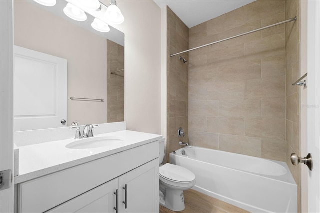 bathroom with toilet, vanity, wood finished floors, and shower / bathtub combination