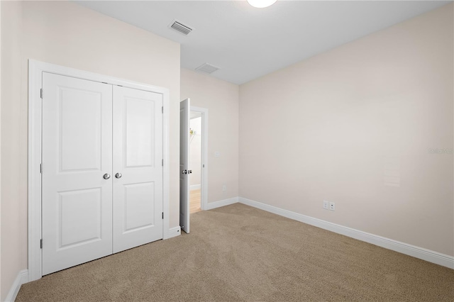 unfurnished bedroom featuring light colored carpet, a closet, visible vents, and baseboards