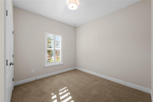 carpeted spare room featuring baseboards