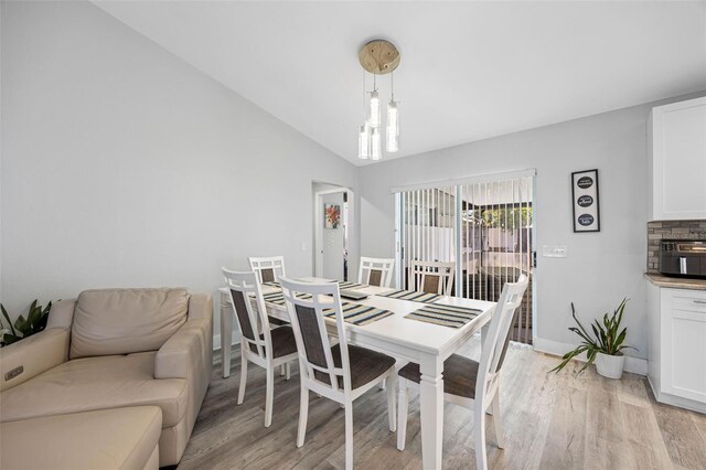 dining room featuring vaulted ceiling, light wood-style flooring, and baseboards