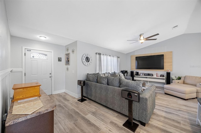 living area featuring visible vents, light wood-style floors, a ceiling fan, vaulted ceiling, and baseboards