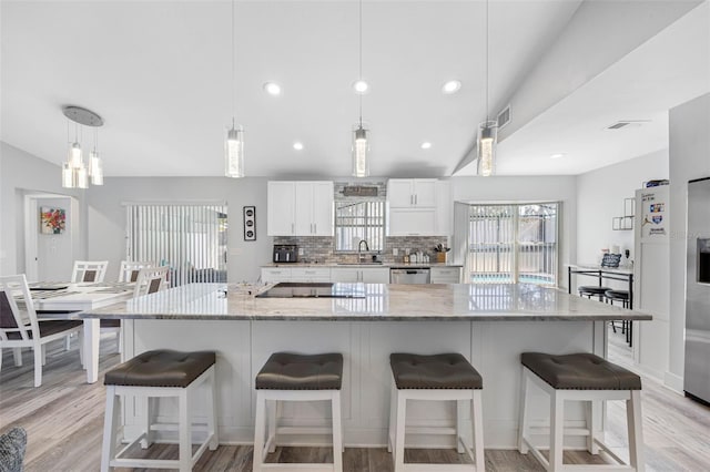 kitchen with black electric stovetop, decorative backsplash, white cabinetry, a sink, and light wood-type flooring