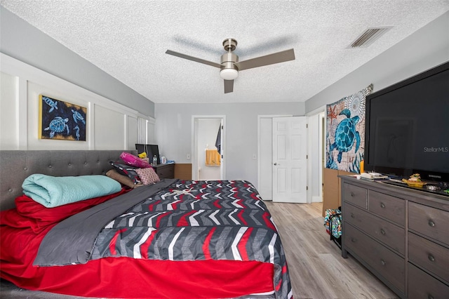 bedroom featuring visible vents, ceiling fan, a textured ceiling, and light wood finished floors