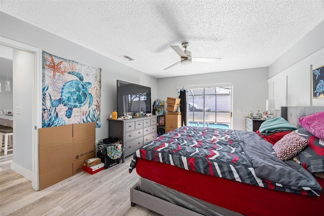 bedroom featuring ceiling fan, a textured ceiling, wood finished floors, and visible vents