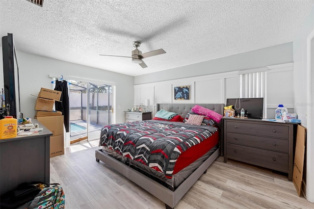 bedroom featuring access to exterior, ceiling fan, a textured ceiling, and wood finished floors