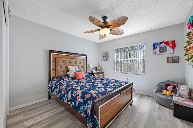 bedroom featuring ceiling fan, a textured ceiling, baseboards, and wood finished floors