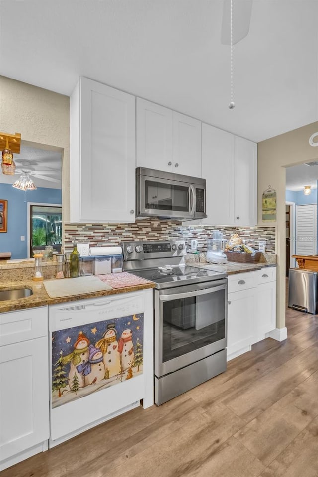 kitchen with stainless steel appliances, tasteful backsplash, stone countertops, white cabinets, and light wood-type flooring