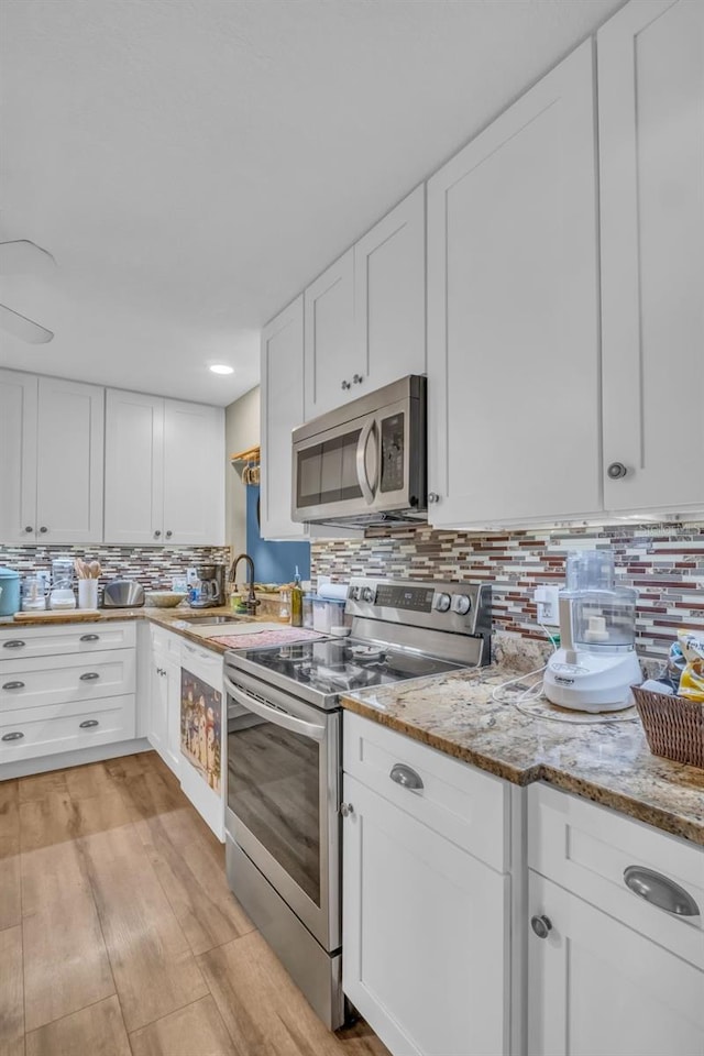 kitchen with appliances with stainless steel finishes, white cabinetry, and tasteful backsplash